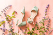 Pastel mint green sandals shoes and meadow flowers on pink. Fashion - summer footwear for woman.