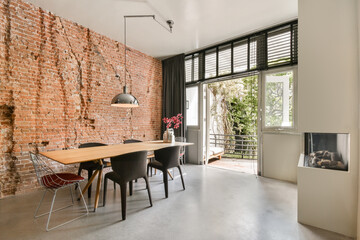 Contemporary minimalist style interior design of light studio apartment with wooden table and chairs in dining zone between open kitchen and living room with white walls and parquet floor