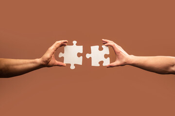 Two hands trying to connect couple puzzle piece on gray background. Teamwork concept. Closeup hand of connecting jigsaw puzzle