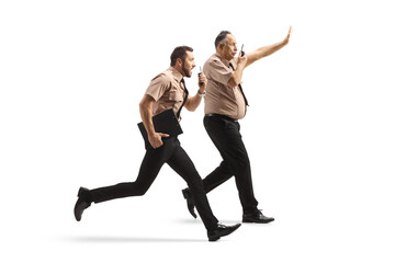 Canvas Print - Full length profile shot of two security guards running and using walkie talkie