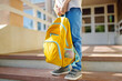 Little student with a backpack on the steps of the stairs of school building. Close-up of child legs, hands and schoolbag of boy standing on staircase of schoolhouse.Back to school concept.