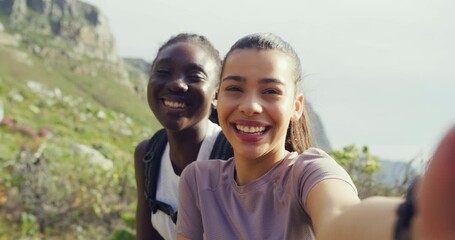 Wall Mural - Two girl friends taking a selfie while hiking on a mountain trail outdoors. Happy women smiling and laughing while taking pictures with a nature view in the background. Getting fit and staying active