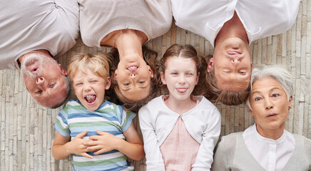 Poster - A family bonding together and being playful, showing different expressions while bonding and enjoying quality time. Above happy fun family making silly faces lying together on a living floor at home.