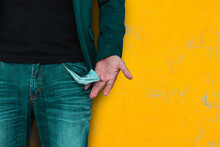 Man Showing His Empty Pocket On Yellow Wall Background.