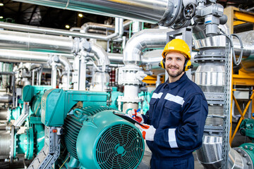 Wall Mural - Portrait of smiling caucasian factory worker standing in oil and gas refinery plant.