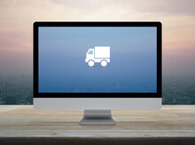 Delivery Truck Flat Icon On Desktop Modern Computer Monitor Screen On Wooden Table Over City Tower And Skyscraper At Sunset Sky, Vintage Style, Business Transportation Online Concept