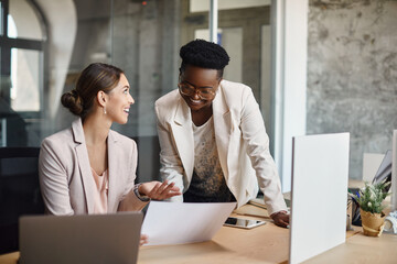 Wall Mural - Happy businesswomen talk while analyzing plans and working in office.