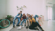 © silverkblack - Young friends sitting on sofa smiling and showing thumbs up all together at home indoors