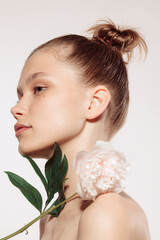 Beauty portrait of charm young girl with flower isolated over white studio background. Cosmetics, natural beauty and aesthetic cosmetology concept.