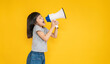© paulaphoto - Portrait of young fun smart happy little asian girl isolated on yellow studio shot. Education for elementary kindergarten, little girl hold megaphone loudspeaker back to school concept.