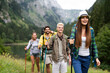 © NDABCREATIVITY - Group of friends with backpacks doing trekking excursion on mountain