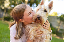 Close-up Of Happy Caucasian Mid Adult Lesbian Woman Kissing Scottish Terrier While Enjoying In Yard