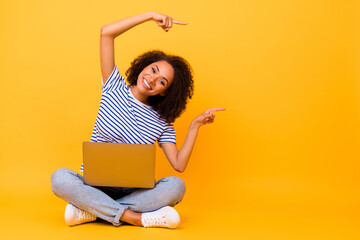 Full body portrait of attractive positive girl indicate fingers empty space use netbook isolated on yellow color background
