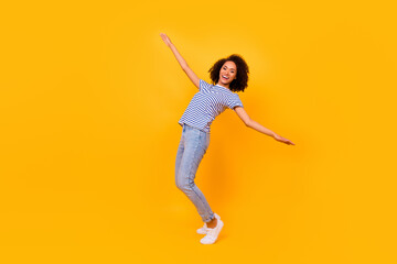 Wall Mural - Full length portrait of overjoyed positive lady stand tiptoe enjoy good mood isolated on yellow color background