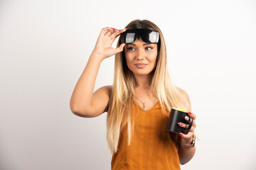 Wall Mural - Young woman holding black cup and wearing goggles