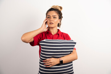 Wall Mural - Woman in red shirt hugging a pillow on white background