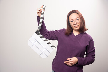 Wall Mural - Young woman posing with a cinema tape on a white background