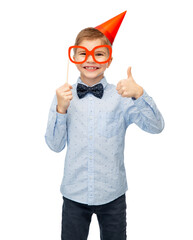 Wall Mural - birthday, childhood and people concept - portrait of little boy in party hat with glasses showing thumbs up over white background