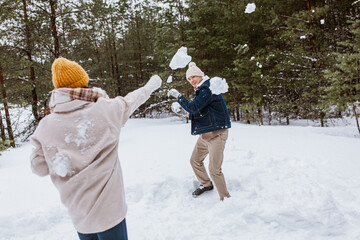 Canvas Print - people, season and leisure concept - happy couple playing snowballs in winter park