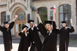 © LIGHTFIELD STUDIOS - Excited student in bachelor gown holding diploma near multiethnic friends outdoors.