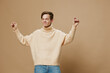 © Tatiana - a happy, joyful young man with red hair, in a long sweater, dances merrily. Studio photography on a plain background with empty space for an advertising layout