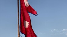 An Upward Panning View Of The Nepali Flag Blowing In The Wind.