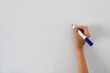 © Marta Nogueira - Close-up of female's hand holding a blue marker writing or drawing on white board. Background with the concept of business or education with empty space for text on the left