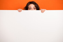 Portrait Of Puzzled Person Eye Peeking Behind Empty Space Blank Isolated On Orange Color Background