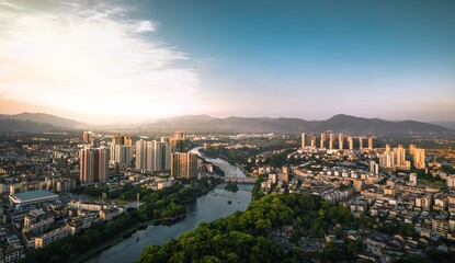 Cityscape view of urban city builings and bridge on a river against a sunny bkue sky on the horizon