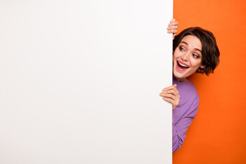 photo of excited funky girl peeking look interested empty space blank promo isolated on orange color
