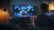 © Gorodenkoff - Young Man Spending Time at Home, Sitting on a Couch in Stylish Loft Apartment and Playing Arcade Car Video Games on Console. Male Using Controller to Play Street Racing Drift Simulator.
