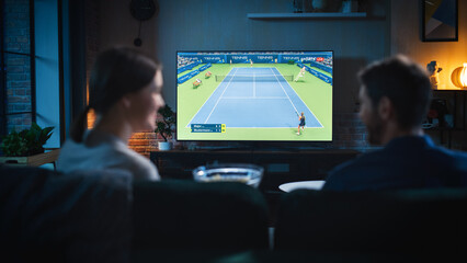 Wall Mural - Authentic Couple Spending Time at Home, Sitting on a Couch and Watching Tennis Championship on Flat Screen Television Set. Man and Woman Enjoying Live Broadcast of Sports Finals.