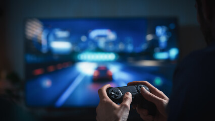 Close Up on Man's Hands at Home, Sitting on a Couch in Stylish Loft Apartment and Playing Arcade Car Video Games on Console. Male Using Controller to Play Street Racing Drift Simulator.