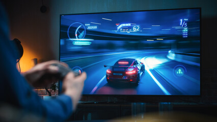 Wall Mural - Close Up on Man's Hands at Home, Sitting on a Couch in Stylish Loft Apartment and Playing Arcade Car Video Games on Console. Male Using Controller to Play Street Racing Drift Simulator.