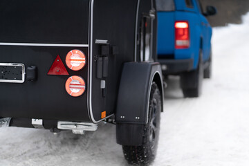 Red stop signal lights on camper towed in the winter woods. Family journey time together away in the forest wild life. Truck with RV travel trailer driving though Park. Family journey concept. 