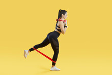 Happy Fit Woman Isolated On Yellow Enjoying Fitness Workout. Full Length Profile Shot Of Beautiful Athletic Lady In Sportswear Doing Exercise With Resistance Band And Dumbbells. Body Training Concept