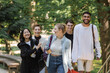 © LIGHTFIELD STUDIOS - Smiling asian student walking near multicultural friends in summer park.