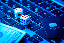 Gambling Background. Making Profit With Online Casino, Online Gaming Concept. Game Dice, Credit Card And Dollars Lie On A Modern Laptop Keypad Close-up.