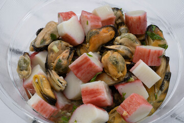 Seafood salads. Health and nutrition. Top view of a fresh salad with sliced kanikama, also known as crab sticks, and mussels, with a provencal dressing. 