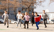 © JackF - Large group of playful children running together at urban landscape