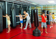 © JackF - Group of kids boxing with punch bags during their group training. Trainer standing nearby and correcting them.