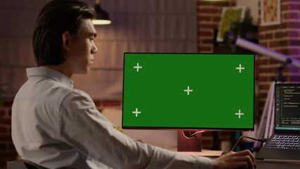 Male freelancer using computer display with greenscreen to work on business. Looking at isolated chroma key template with blank copyspace and mockup background on pc, digital software.