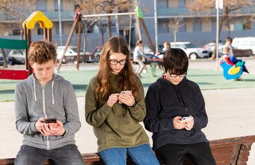 Kids using phones outdoors, concept of children addiction to social network