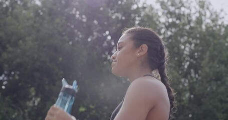 Sticker - A young athletic and active woman hydrating after a workout. Fit sports person refreshing after running. A female athlete drinking water after an exercise outdoors in a park with copy space.