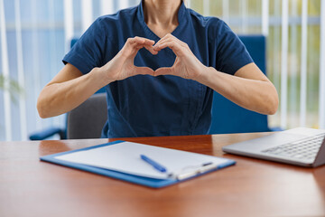 Sticker - Close up of doctor working laptop and showing heart with hands in medical office 