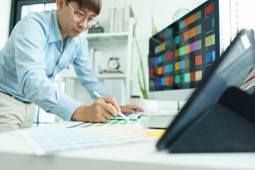 Wall Mural - creativity concept, male graphic designer choosing color swatch samples on document and designing
