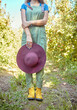© Jade M/peopleimages.com - Closeup apple farmer standing alone on a farm and holding her sun hat. Woman in dungarees surrounded by fresh agricultural fruit trees, produce for harvest on remote sustainable apple orchard