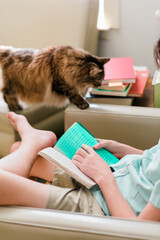 Sticker - Dyslexic child reading with dyslexia color overlay to make a book easy to read. Cat is coming to cuddle. Kid relaxing reading a book.