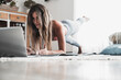 © simona - Fit and healthy lifestyle young woman doing plank position at home looking a lesson on the laptop. Sport and active workout on the web. Following internet channel about body positivity and health
