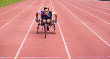 Teenager Crouching In Racing Wheelchair On A Red Athletics Track